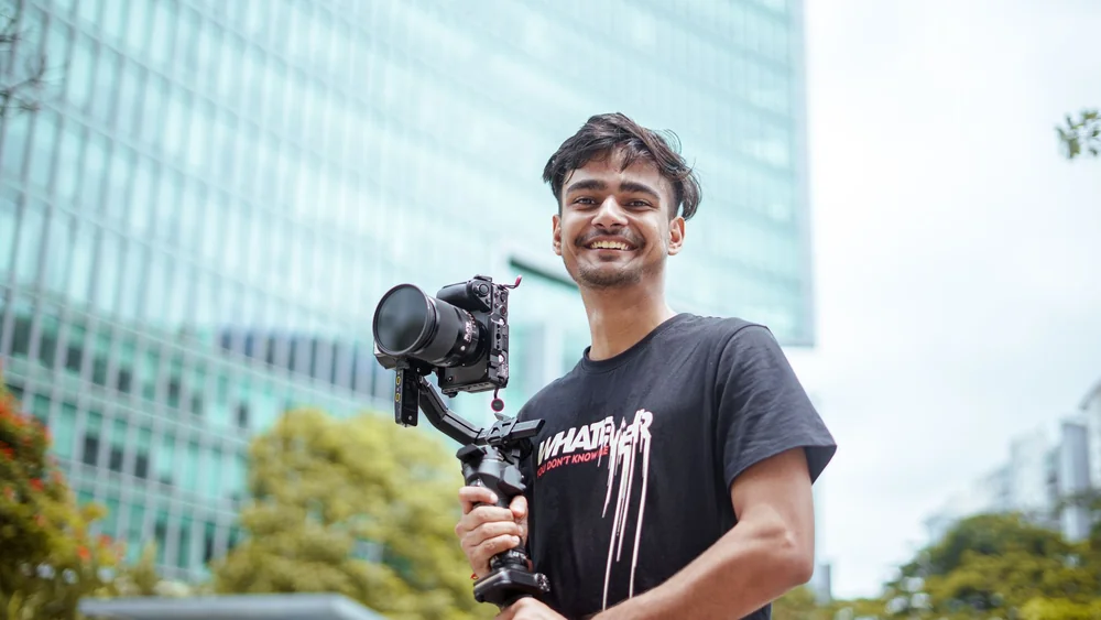 Young man smiling as he films with a camera rig