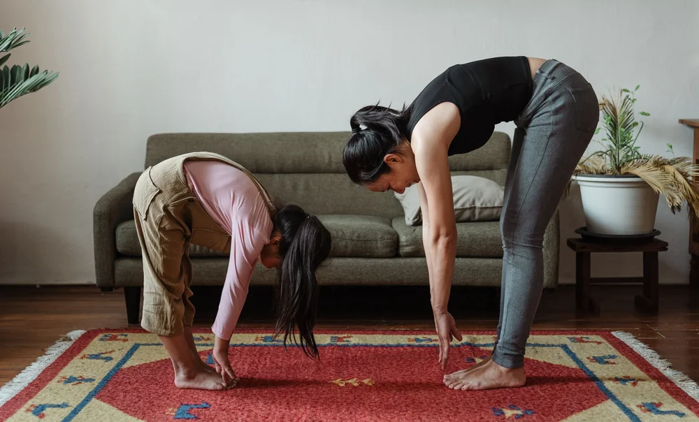 Two women doing a home workout together on a rug in their living room