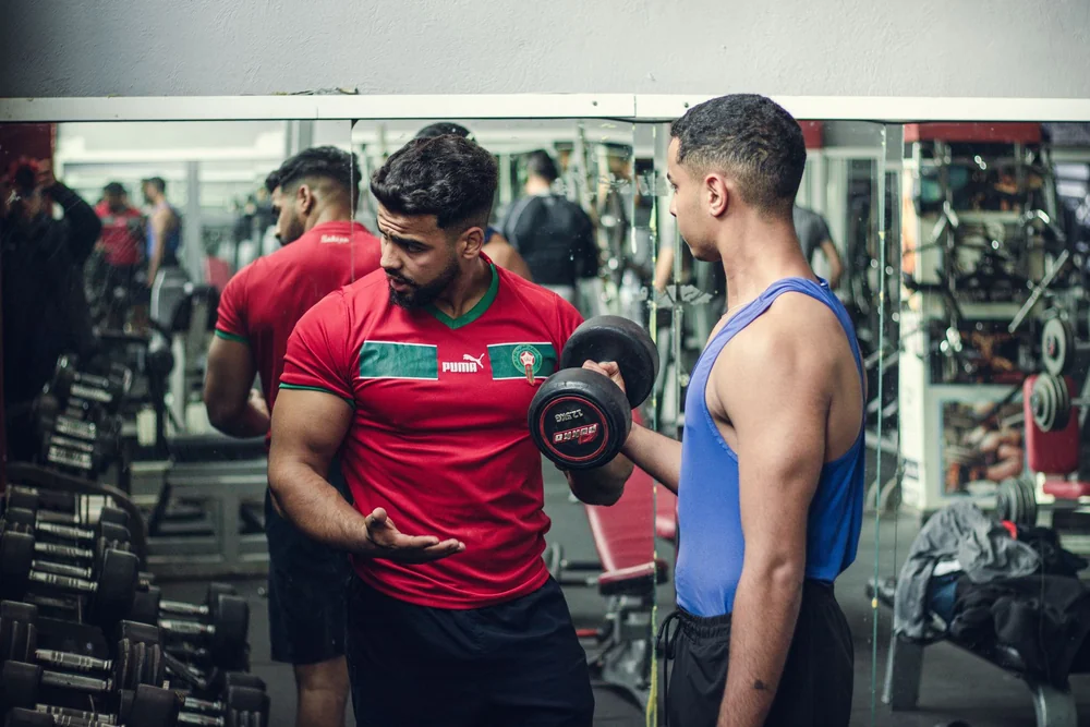 Trainer watching a member's form during a dumbbell exercise