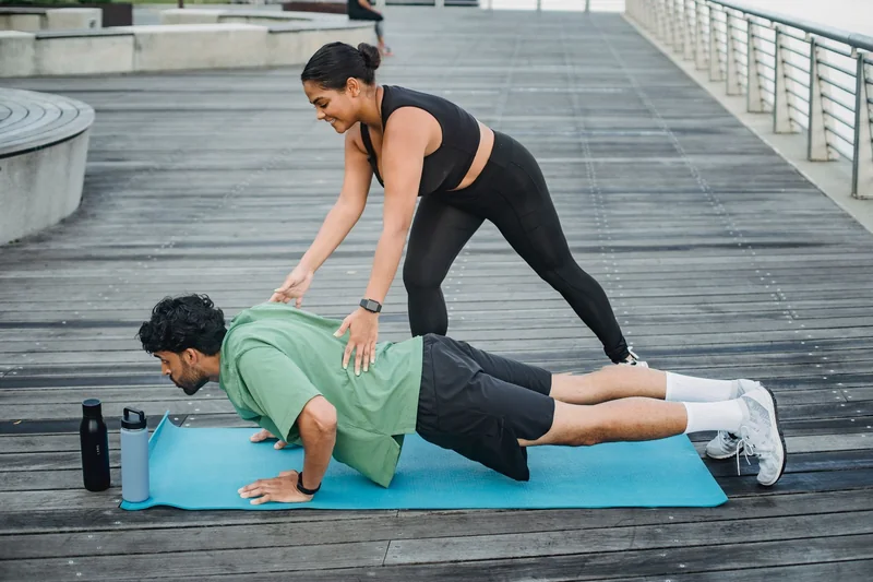 Coach correcting a push-up on an exercise mat